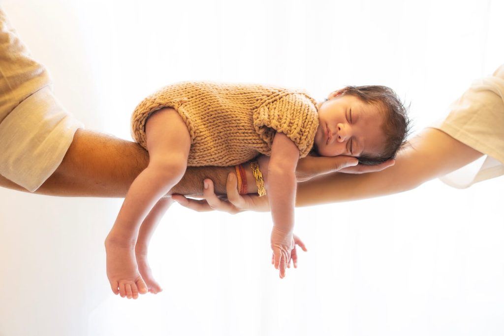 Baby sleeping and posing on parents hands